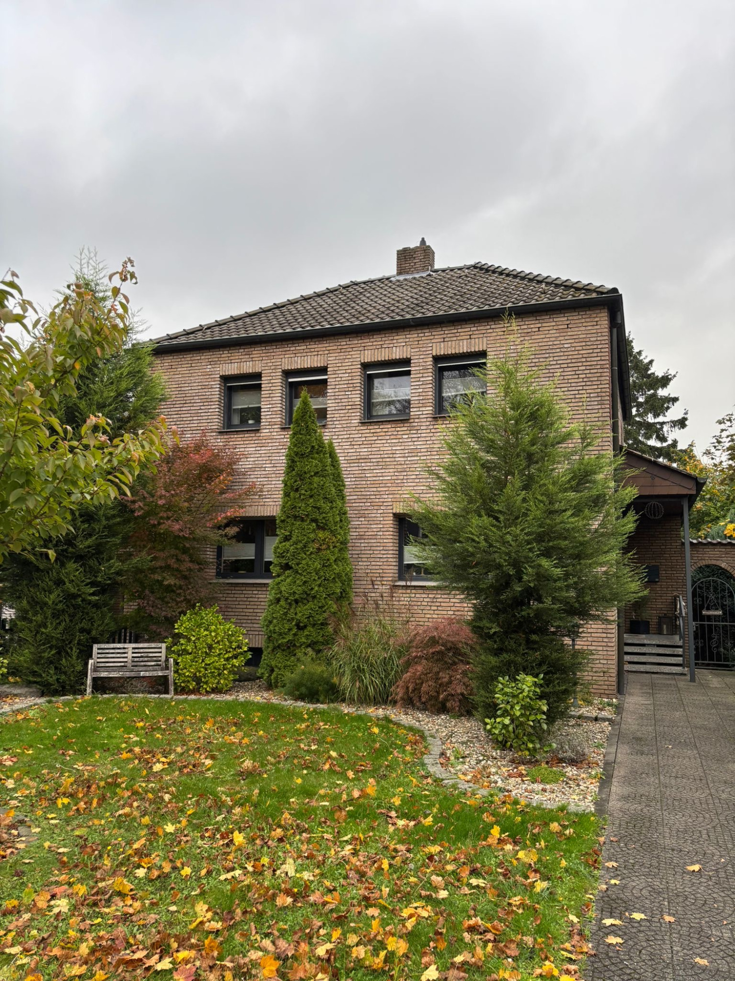 Bestandsgebäude - Projekt F7 Zweistöckiges Haus aus Backstein mit Garten und Laub im Vordergrund.