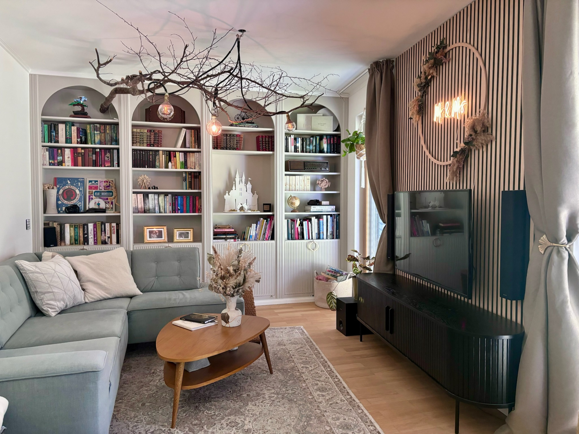 Wohnzimmer - Projekt H9 Heller Wohnbereich mit grauem Sofa, Bücherregal, TV und stilvollen Dekorationselementen.