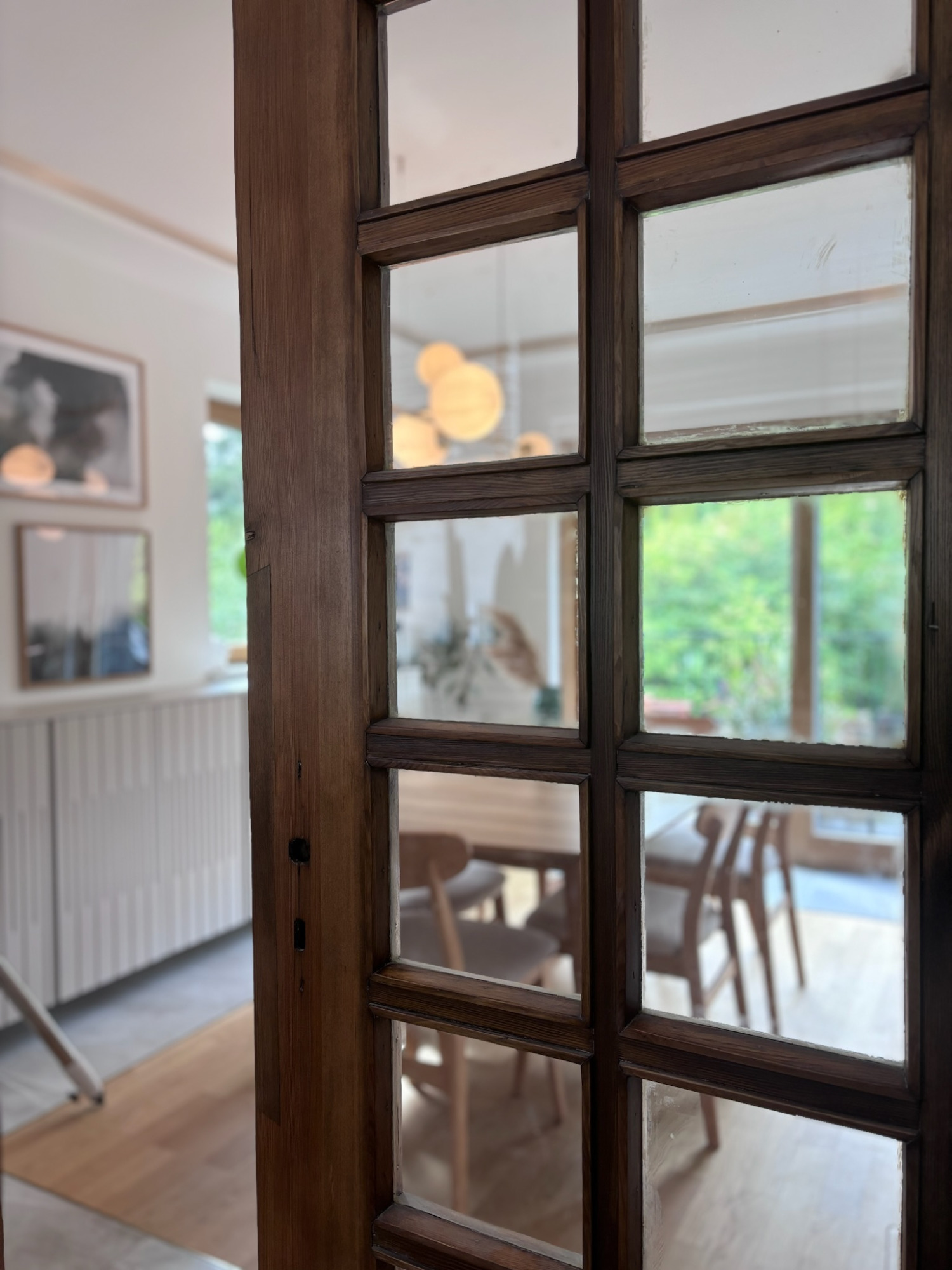 Esszimmer - Projekt H9 Ein Blick durch eine Holzsichttür auf einen hellen Essbereich mit Tisch und Stühlen.