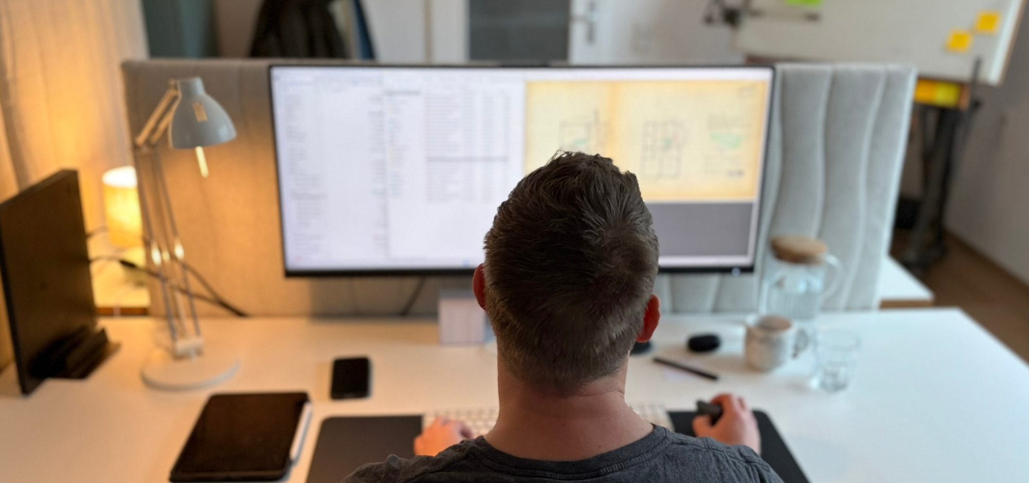Büro Nebel Architektur Person arbeitet am Schreibtisch mit mehreren Bildschirmen und digitalen Geräten.