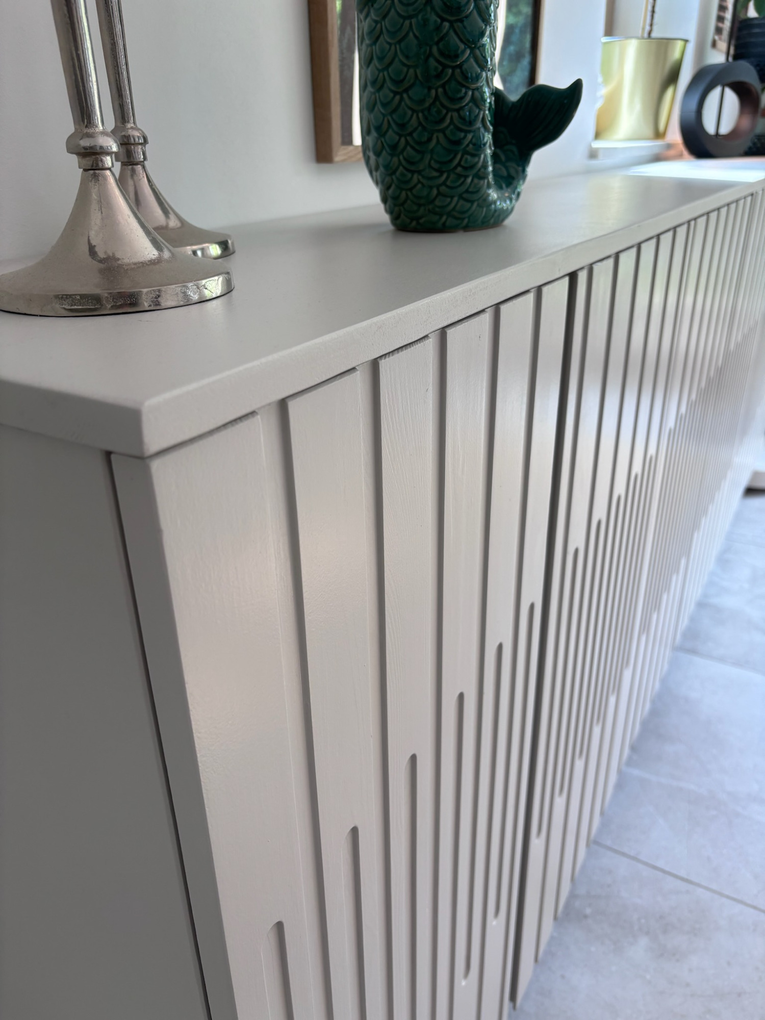 Möbelbau - Projekt H9 Moderne Kommode mit gerillter Oberfläche, daneben eine grüne Vase und ein Kerzenhalter.